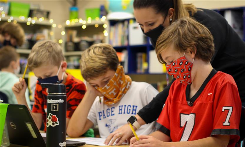 Teacher helps students solve worksheet problems